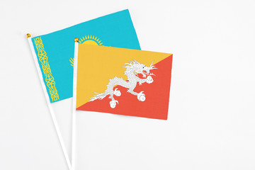 Bhutan and Kazakhstan stick flags on white background. High quality fabric, miniature national flag. Peaceful global concept.White floor for copy space.
