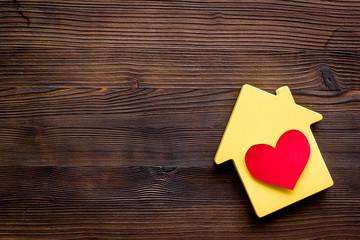 Happy life and home concept. House cutout and heart icon on dark wooden background top view copy space