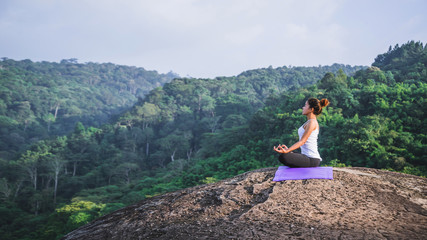 Asian women relax in the holiday. Play if yoga. On the Moutain rock cliff. Nature of mountain forests in Thailand. Young woman practicing yoga in the nature female happiness. exercise yoga