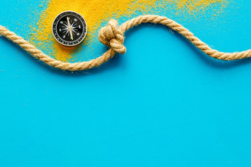 Goal achievement concept. Compass near rope with knot on blue background top view copy space