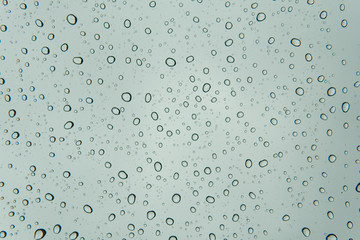 Natural pattern of water rain drops on glass surface with cloudy background. 