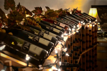 Obraz premium SALEM, OREGON/USA - November 10, 2019: Bottles of wine in a stand in Vitis Ridge Winery with Christmas lights and grapes.