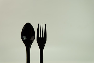 Selective focus of black shine spoon and fork with white background. Food or restaurant concept.