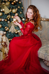 Young beautiful elegant woman standing near the christmas tree. christmas tree with golden ballsю...