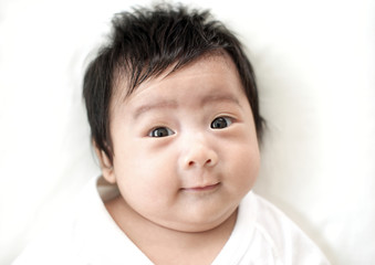 Cute adorable asian newborn looking at camera and smiling on white bed : Closeup