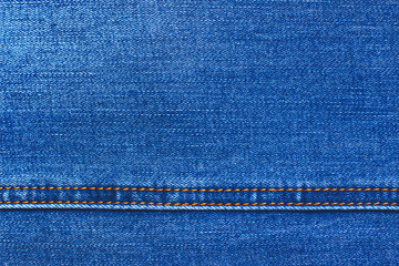 Top view of a blue denim with a beautiful even sewing seam. Yellow thread stitches. Abstract modern trendy texture background. Copy space for text.