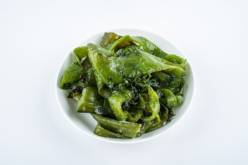 Fresh green salted sea cabbage stems on a saucer on a white background