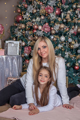 Mother and daughter next to the Christmas tree . Holiday new year and Christmas. Beautiful mom and daughter.