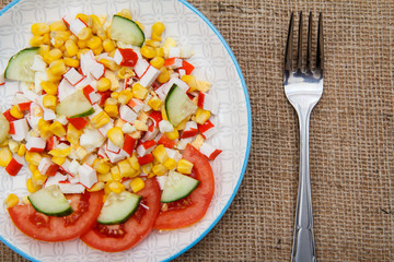 Salad with crab sticks, boiled corn and freshly sliced tomato and cucumber