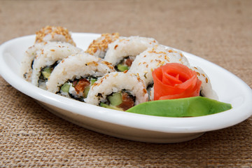 Uramaki sushi rolls with avocado and red fish on ceramic plate