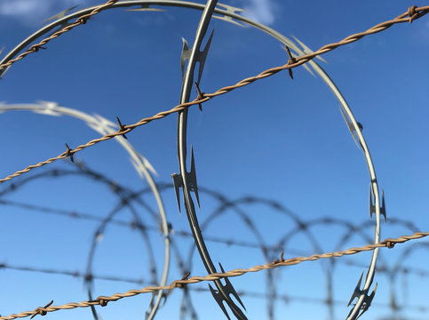 Barbed and Razor Wire Atop a Fence