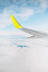 Vertical view of the blue sky and the wing of the plane - white clouds and a silver wing with a...