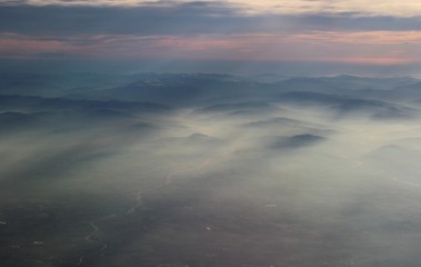 spectacular sunset seen from an airplane with the sun reflecting off a river and the  mountains in the background