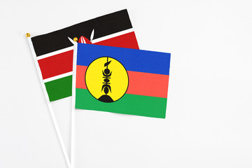 Fototapeta premium New Caledonia and Kenya stick flags on white background. High quality fabric, miniature national flag. Peaceful global concept.White floor for copy space.