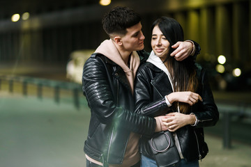 Fototapeta premium Young couple in love hug each other and have fun in underground crossing. Couple of man and woman walking into a tunnel. Happy to be together. Love, romantic, passion, tenderness concept.
