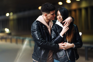 Young couple in love hug each other and have fun  in underground crossing. Couple of man and woman walking into a tunnel. Happy to be together. Love, romantic, passion, tenderness concept.