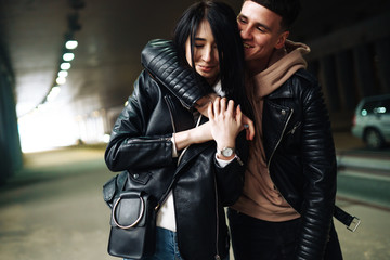 Fototapeta na wymiar Young couple in love hug each other and have fun in underground crossing. Couple of man and woman walking into a tunnel. Happy to be together. Love, romantic, passion, tenderness concept.