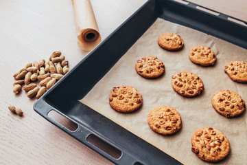 Oven baking tray with round homemade cookies on an oak table
