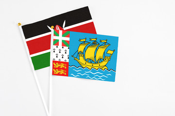 Saint Pierre And Miquelon and Kenya stick flags on white background. High quality fabric, miniature national flag. Peaceful global concept.White floor for copy space.