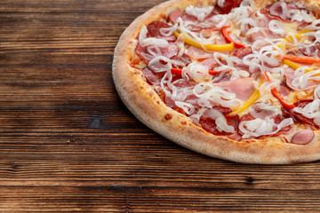 Hot italian meat pizza with sausage, ham and salami and bunch of sweet onion