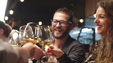 Best friends sitting in restaurant for dinner and making a toast with white wine. On table is food. - Powered by Adobe