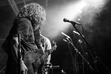 A man with long hair is viewed from low angle view as he holding and playing electric guitar, black...