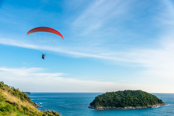 Paragliding Extreme sport, Paraglider flying on the blue sky and white cloud in Summer day at Phuket Sea, Thailand.