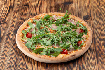Parma ham pizza with fresh arugula and cherry tomatoes on wooden table