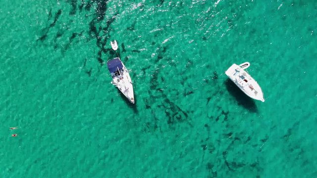 Cenital flight over a couple of yatchs on an amazing transparent clean green waters in Menorca island Spain