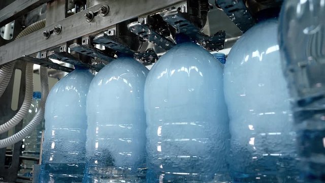 Production of artesian water from natural well in plastic bottle. Automatic conveyor line of bottling distilled technical liquid and covering caps. Factory of manufacturing fresh spring mineral water.