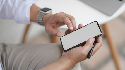 Cropped shot of man holding blank screen smartphone while working the project in outdoor comfortable workplace
