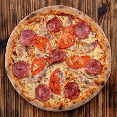 Top view of classic salami pizza with melted cheese on wooden rustic table