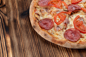 Classic salami pizza with melted cheese on wooden rustic table