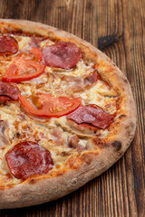Closu up of salami pizza with melted cheese on wooden rustic table