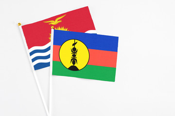 New Caledonia and Kiribati stick flags on white background. High quality fabric, miniature national flag. Peaceful global concept.White floor for copy space.