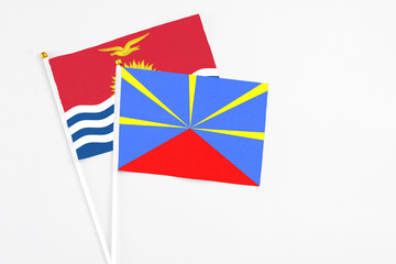 Reunion and Kiribati stick flags on white background. High quality fabric, miniature national flag. Peaceful global concept.White floor for copy space.