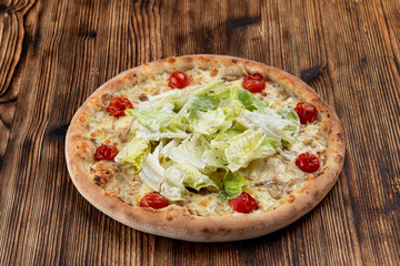 Chicken pizza with chicken breast, cherry tomatoes and fresh chinese cabbage on wooden table