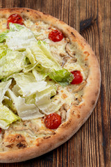 Chicken pizza with chicken breast, cherry tomatoes and fresh chinese cabbage on wooden table