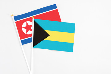 Bahamas and North Korea stick flags on white background. High quality fabric, miniature national flag. Peaceful global concept.White floor for copy space.