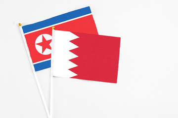 Obraz premium Bahrain and North Korea stick flags on white background. High quality fabric, miniature national flag. Peaceful global concept.White floor for copy space.