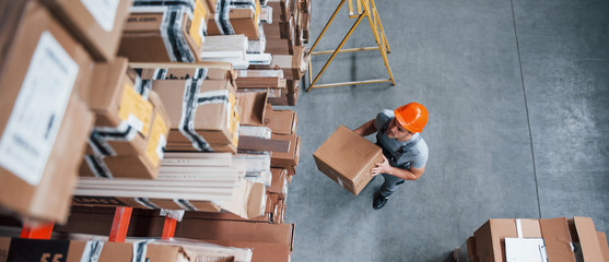 Top view of male worker in warehouse with box in hands