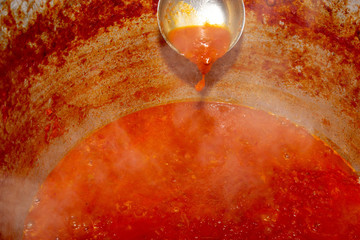 liquid red tomato in an iron cauldron on a healed plate