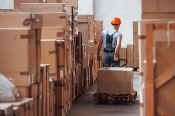 Young male worker in uniform is in the warehouse with pallet truck © standret