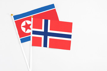 Obraz premium Bouvet Islands and North Korea stick flags on white background. High quality fabric, miniature national flag. Peaceful global concept.White floor for copy space.