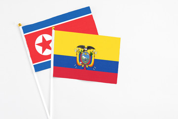Ecuador and North Korea stick flags on white background. High quality fabric, miniature national flag. Peaceful global concept.White floor for copy space.