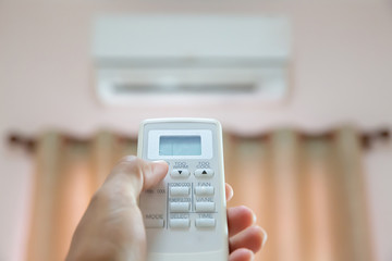 Close up hand and remote control air condition.