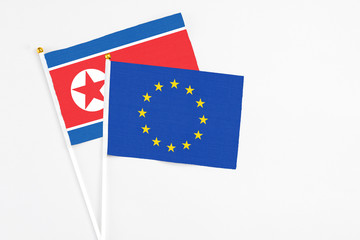 European Union and North Korea stick flags on white background. High quality fabric, miniature national flag. Peaceful global concept.White floor for copy space.