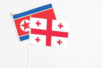 Georgia and North Korea stick flags on white background. High quality fabric, miniature national flag. Peaceful global concept.White floor for copy space.