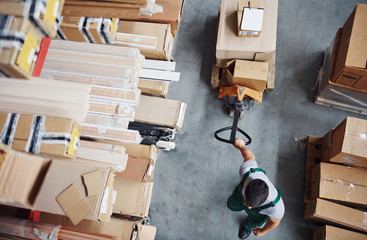 Top view of male worker in warehouse with pallet truck