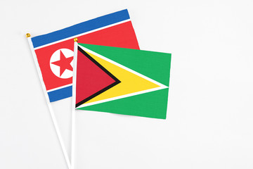 Guyana and North Korea stick flags on white background. High quality fabric, miniature national flag. Peaceful global concept.White floor for copy space.